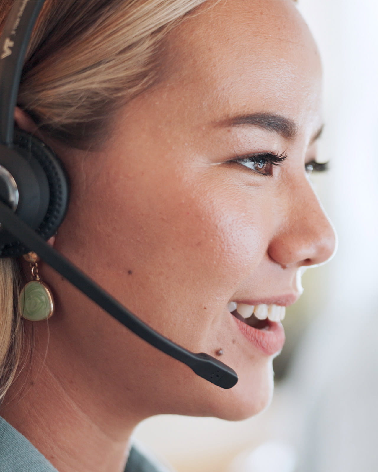 A customer care representative smiling with a headset on.